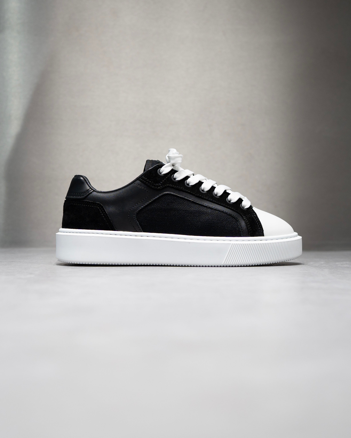 Black and white leather low-top sneakers with white laces and rubber sole