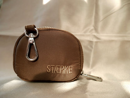 Espresso-brown round zip jewelry pouch with silver clasp hardware and gold logo text