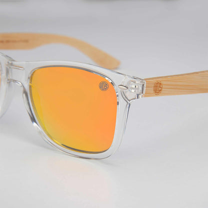 XL sunglasses close-up: orange mirrored lens, clear frame, wood-look temple arm