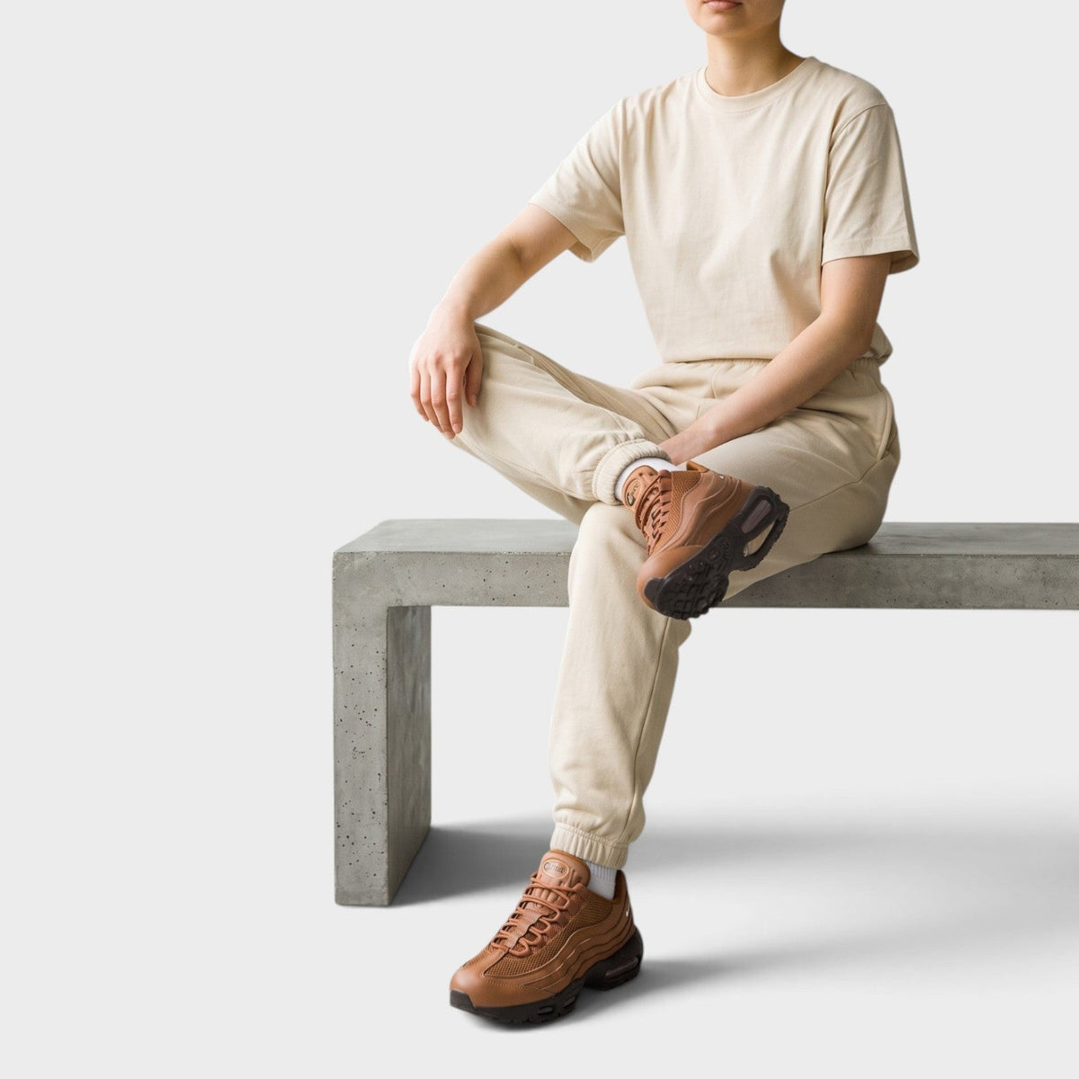 Tan Air Max sneakers on model’s feet with jogger pants; lace-up design and air unit