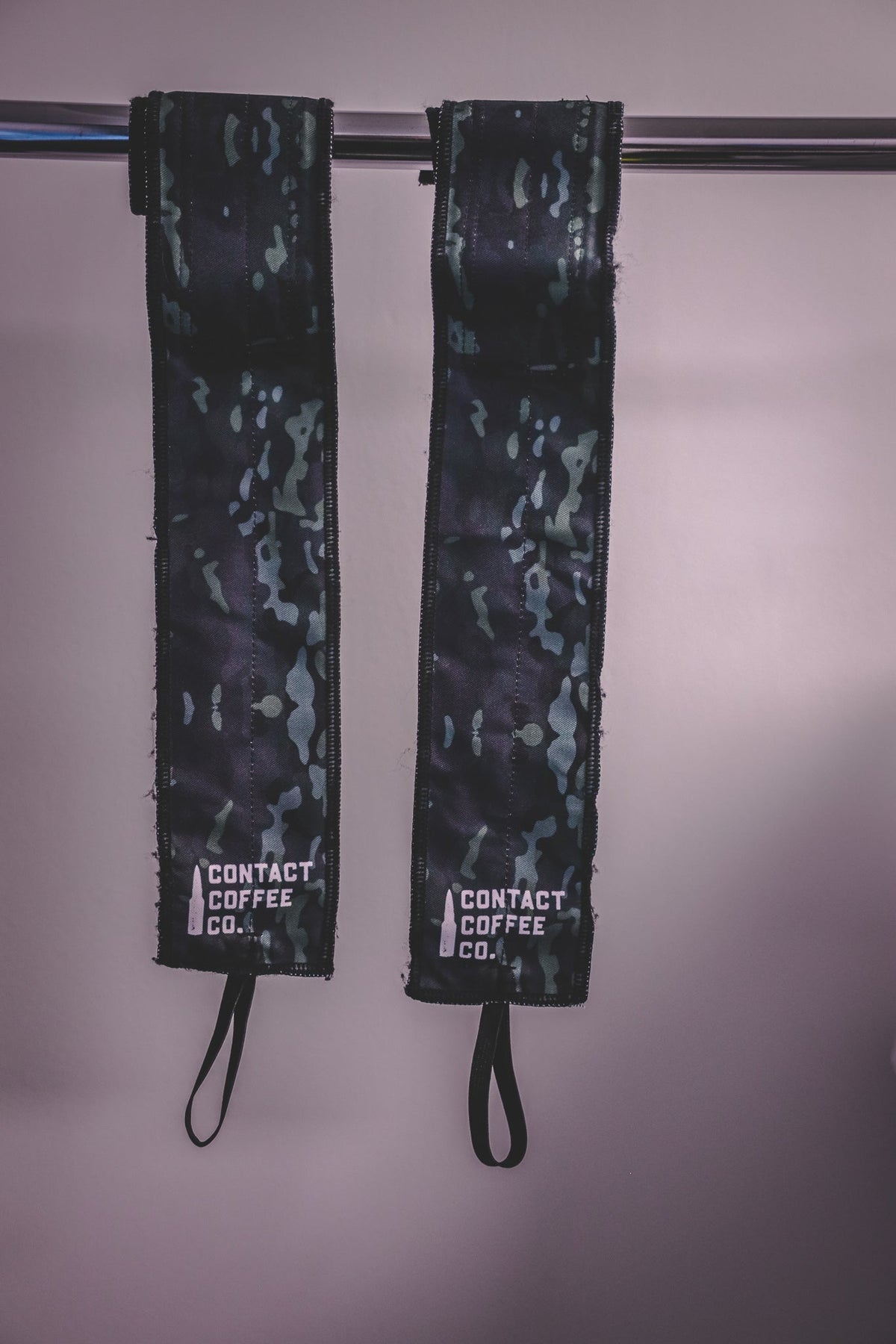 Pair of black and green camo gym wrist wraps hanging with drawstring loops