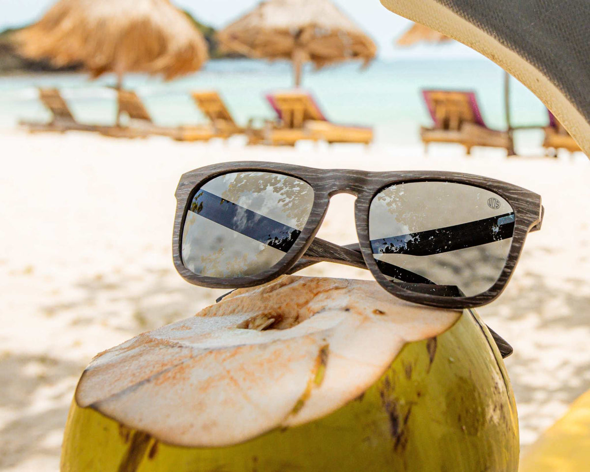 Polarised sunglasses with dark lenses on a beach, brown woodgrain-style frame