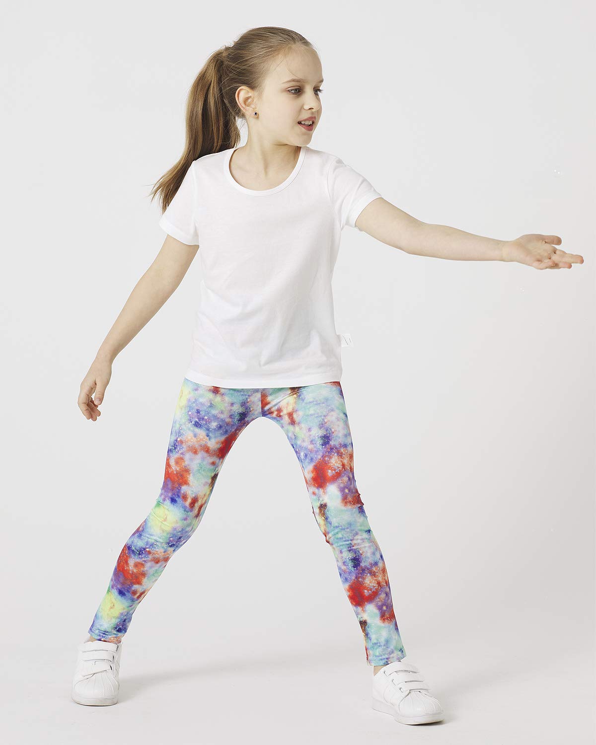 Girls' galaxy leggings worn with a white top; multicolor nebula print and white shoes