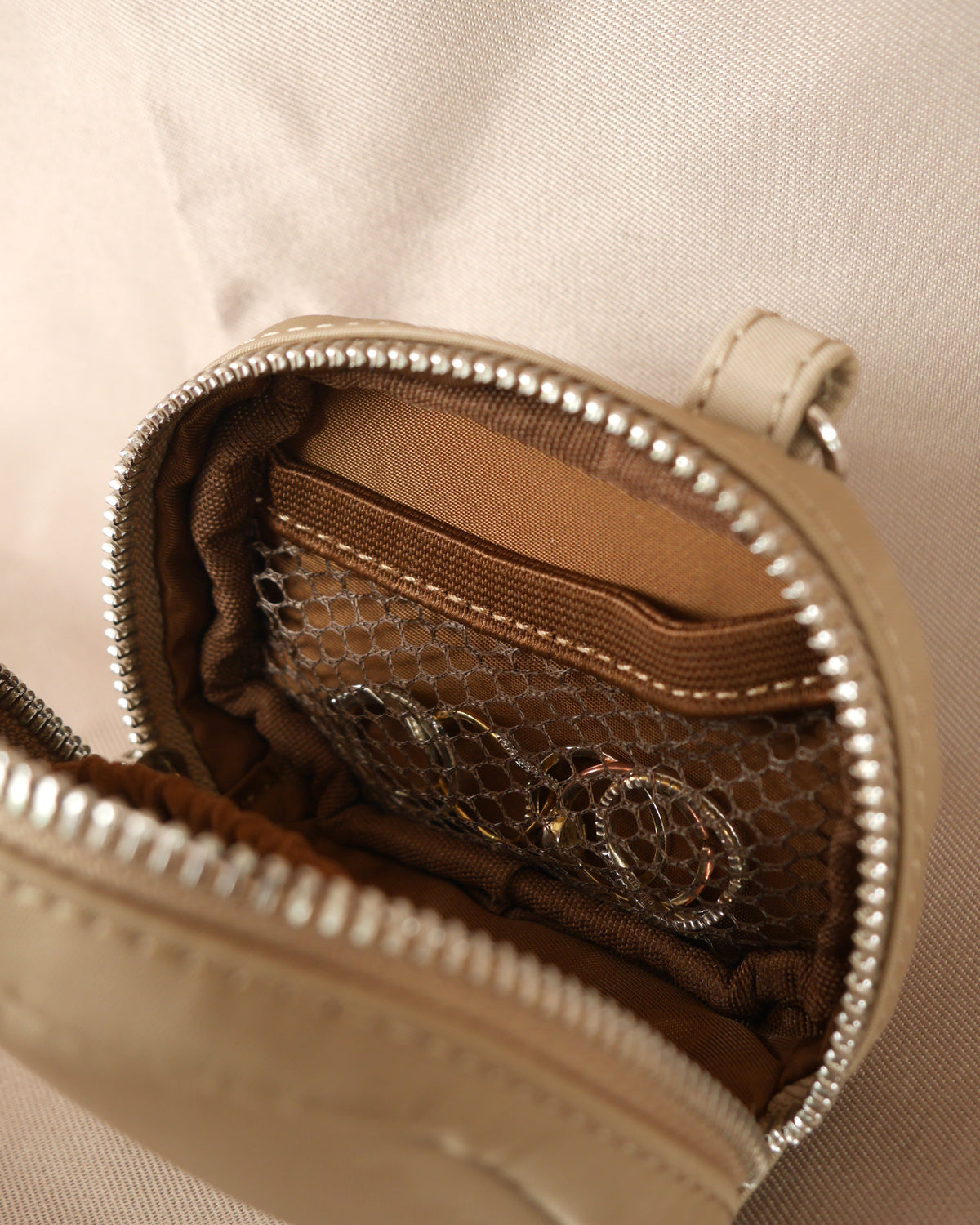 Espresso-brown zip jewelry pouch with interior patterned lining and silver zipper hardware
