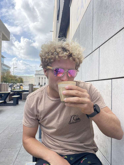 Eco friendly sunglasses on a person, with clear frame and purple mirrored lenses