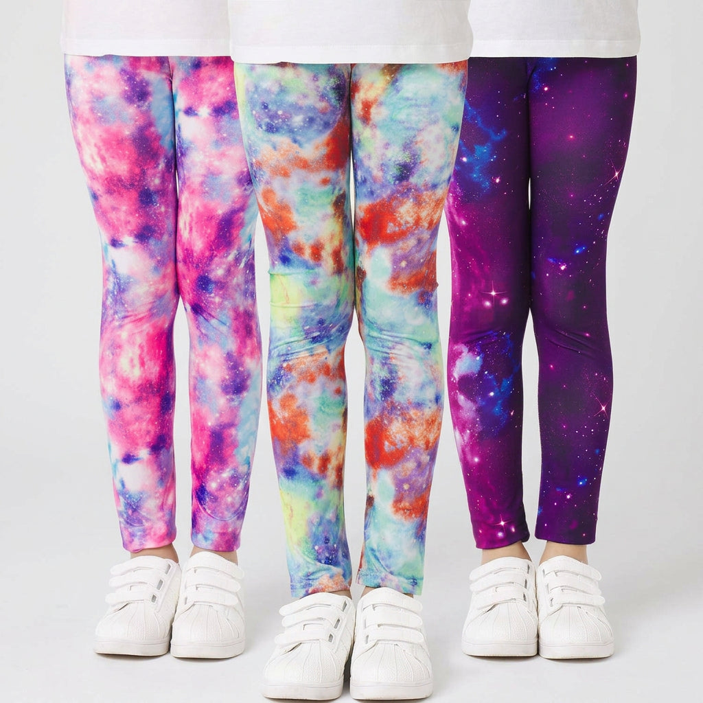 Three pairs of kids' leggings with vibrant tie-dye and galaxy prints, shown on models from the waist down wearing white sneakers against a white background.
