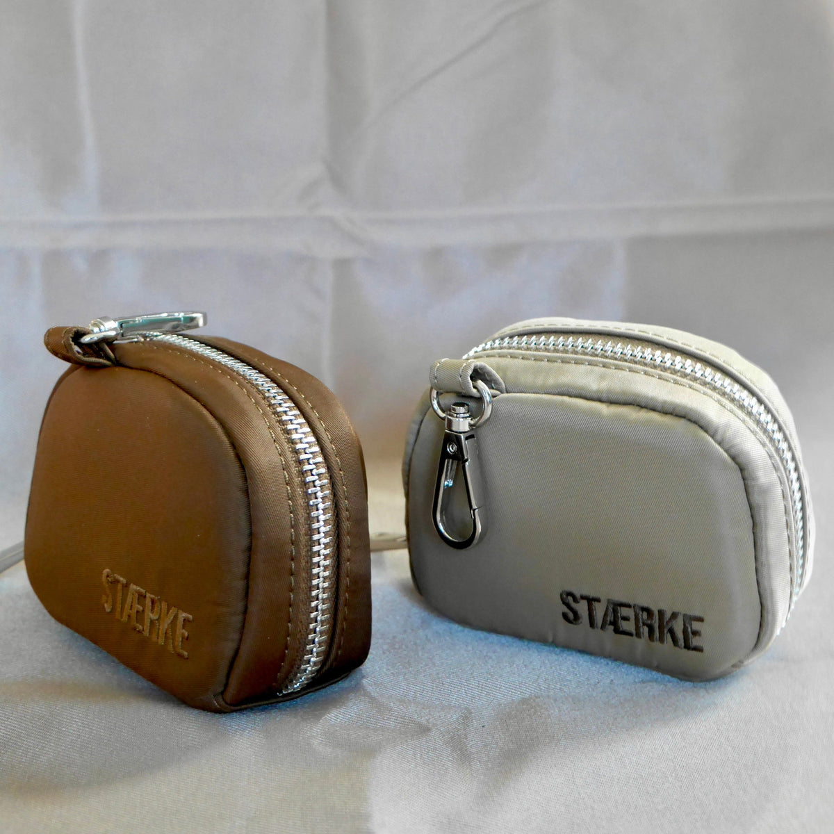 Two small zip jewelry pouches: espresso and sand, each with silver zipper and clasp