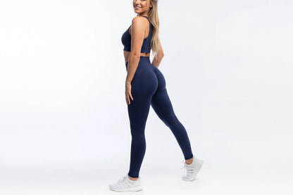 Person wearing navy blue leggings and white sneakers on a white background