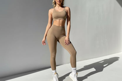 Woman wearing a beige sports bra and leggings set on a plain background