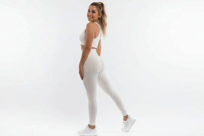 Person wearing white leggings and white sneakers on a plain background