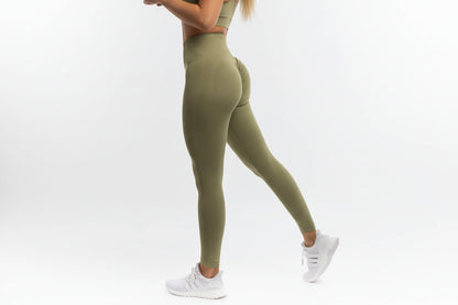 Person wearing olive green leggings and white sneakers on a white background