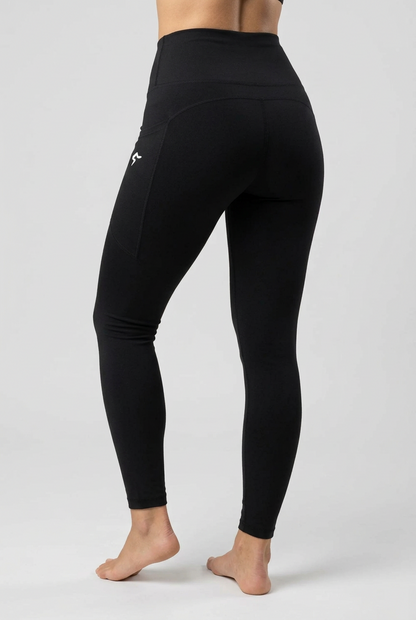 Black high-waisted leggings with a small white logo on the left hip, shown on a model from a rear three-quarter angle against a light beige background.