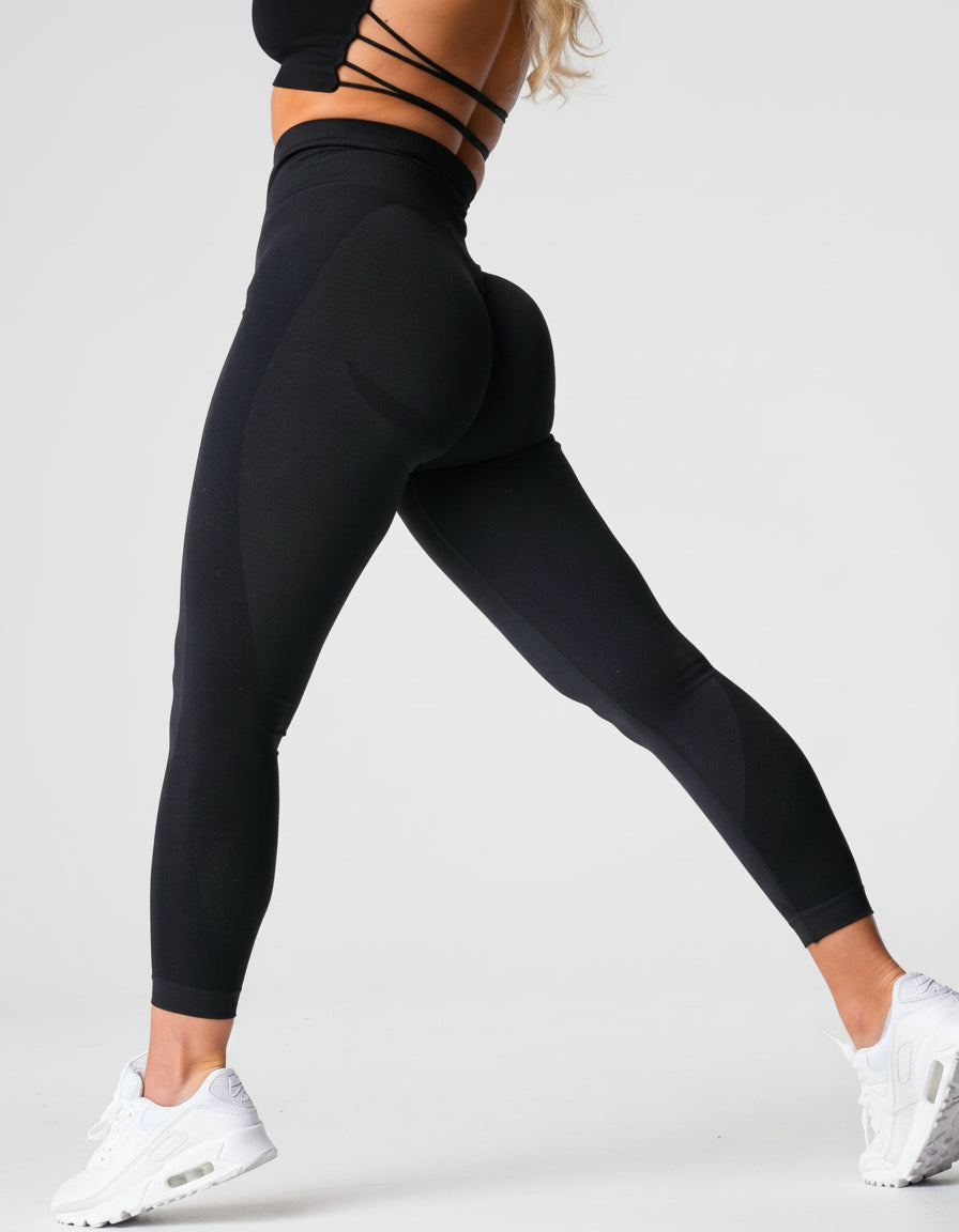 Person wearing black leggings and white sneakers on a plain background