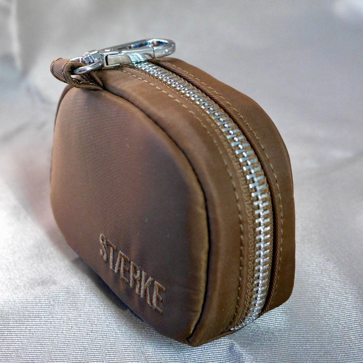 Espresso-brown zip jewelry pouch with silver zipper around the rounded front