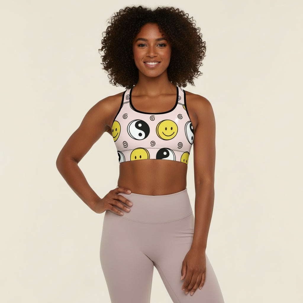 Woman wearing a sports bra with smiley face and yin yang design on a beige background