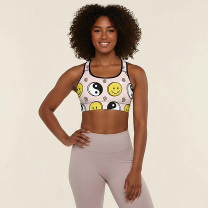 Woman wearing a sports bra with smiley face and yin yang design on a beige background
