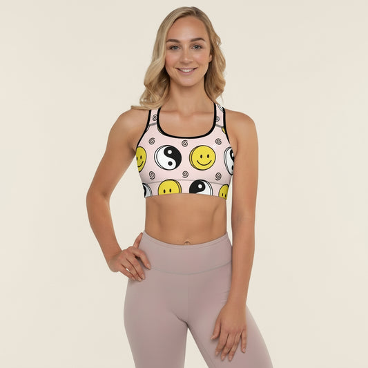 Woman wearing a sports bra with smiley face and yin yang design on a beige background