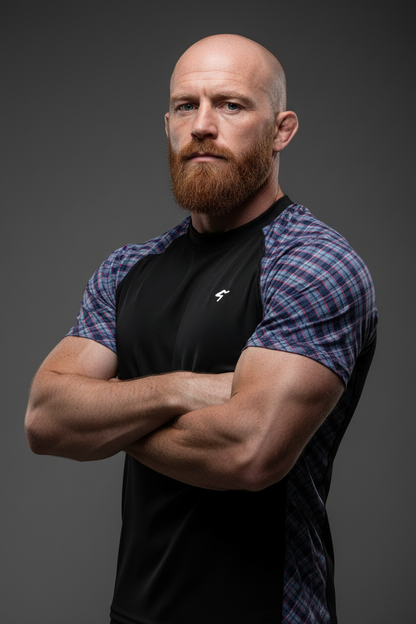 Man with a beard wearing a black and plaid shirt against a dark background