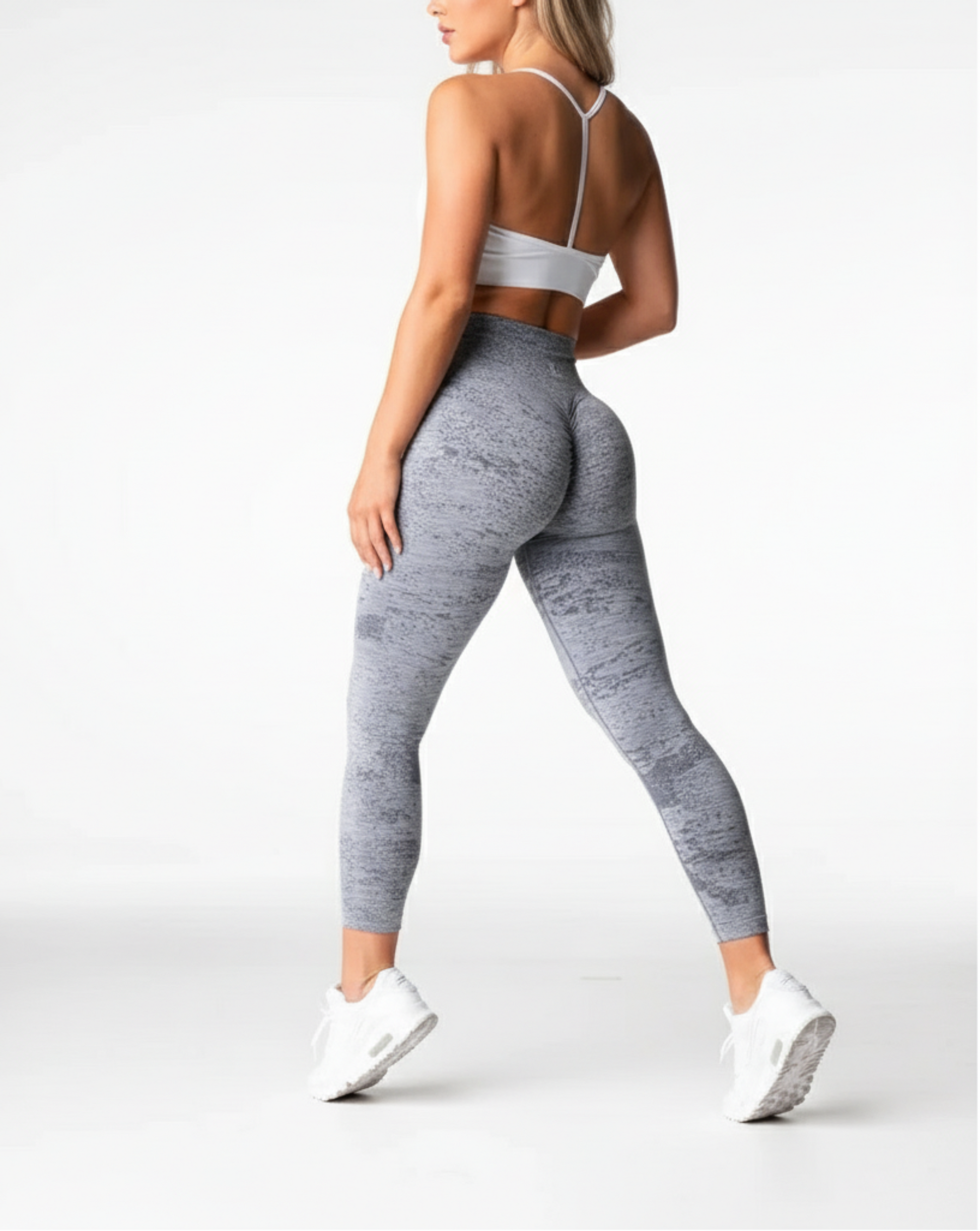 Person wearing gray leggings and white sneakers on a white background