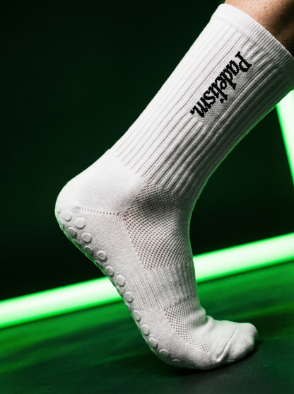 White crew socks featuring Padelism logo and gray grip dots on the sole