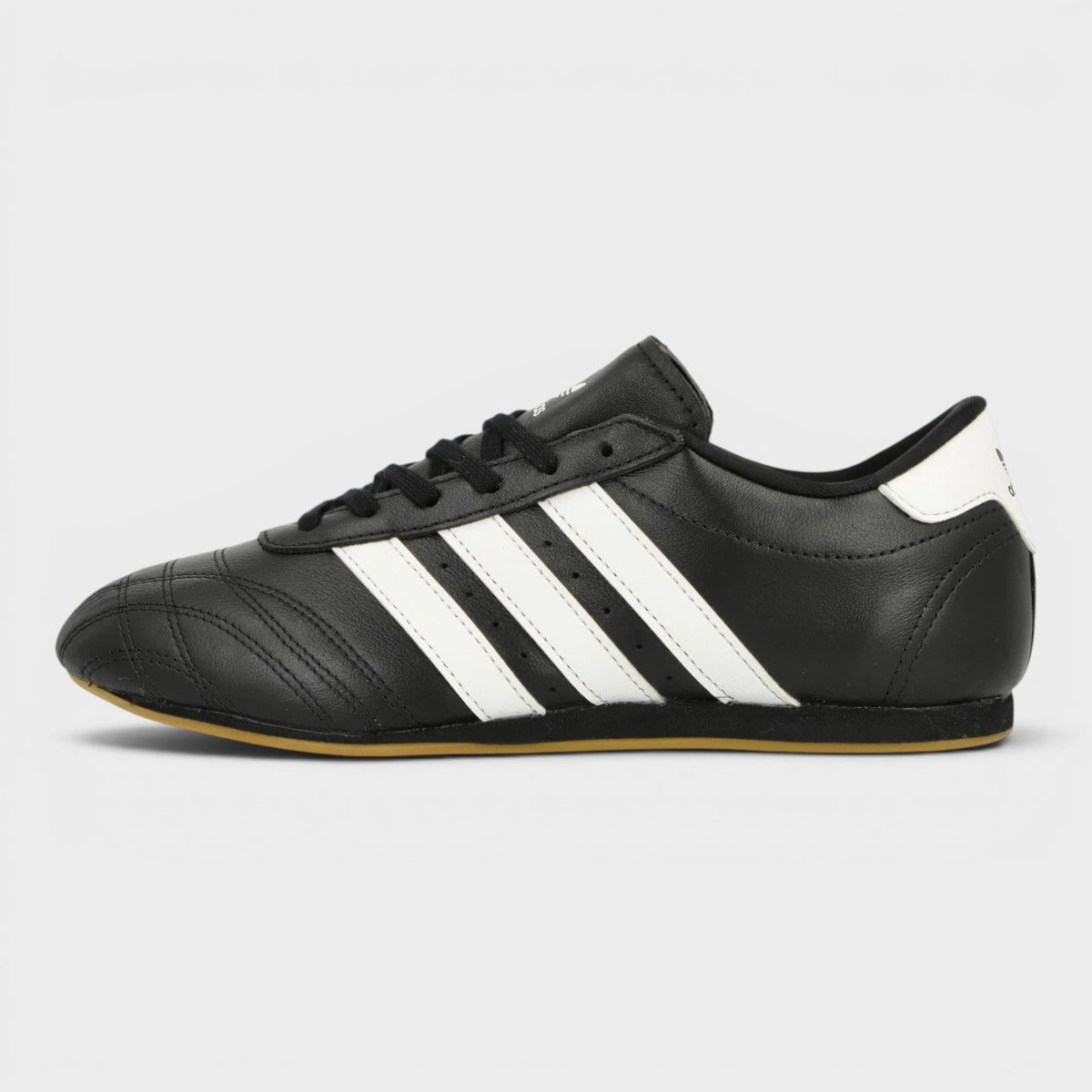Black taekwondo shoes, side view, three white stripes and gum sole