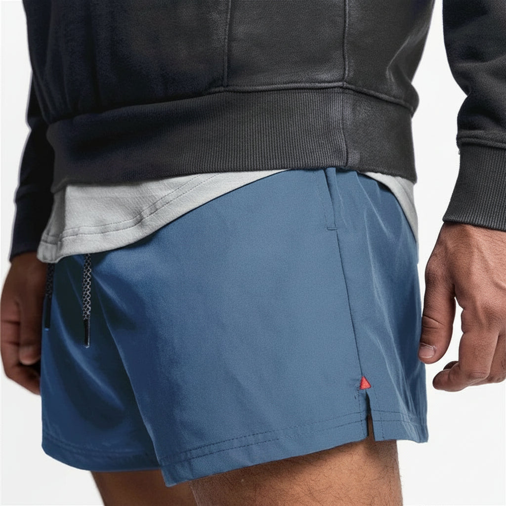 Person wearing blue shorts with a small red triangle logo on a white background