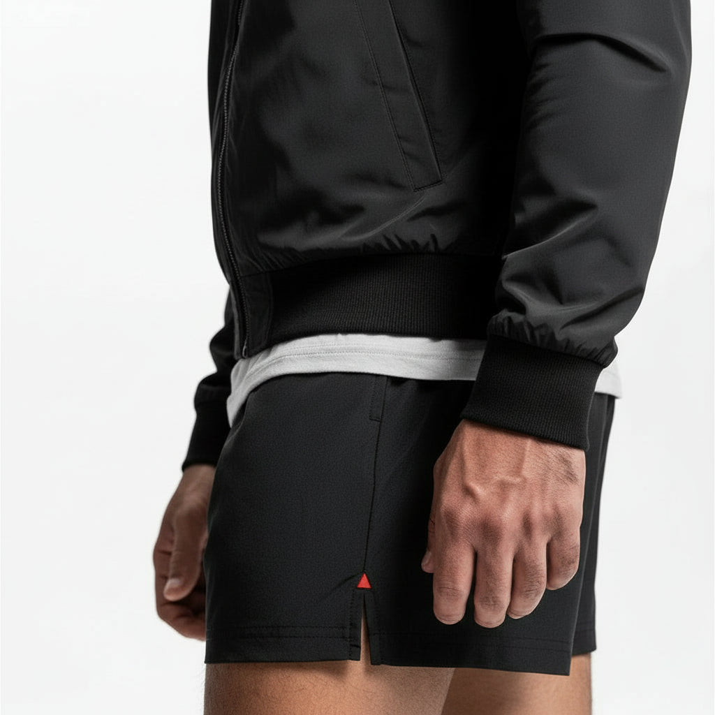 Person wearing a black hoodie and black shorts on a white background