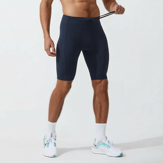 A man wearing navy Quick Dry Compression Shorts with an elastic waist, standing and facing away from the camera. He is also wearing white sneakers.