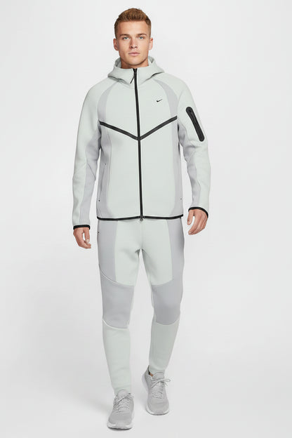 Man wearing a light gray Nike hoodie with black accents on a white background