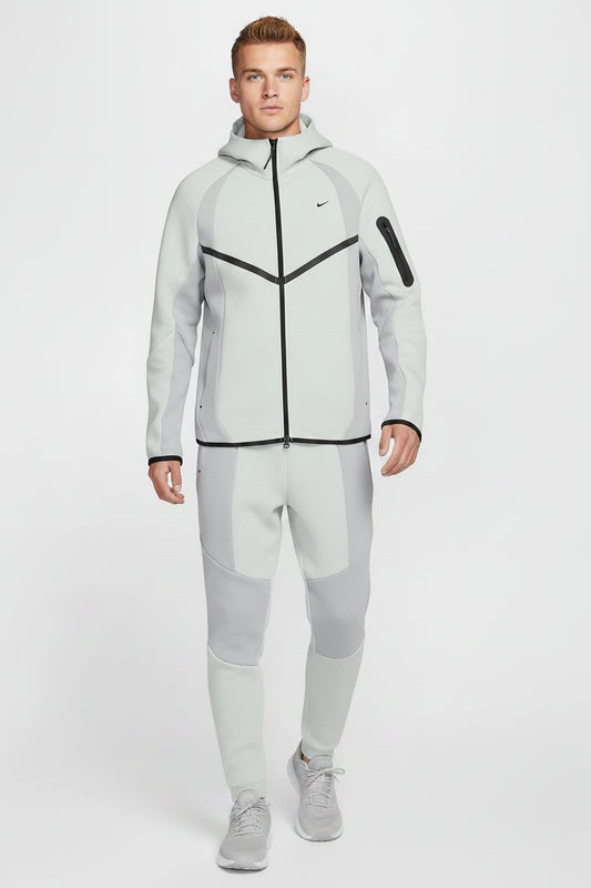 Man wearing a light gray Nike hoodie with black accents on a white background
