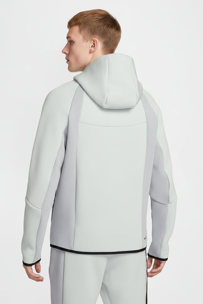Person wearing a light gray hoodie with a hood on a white background