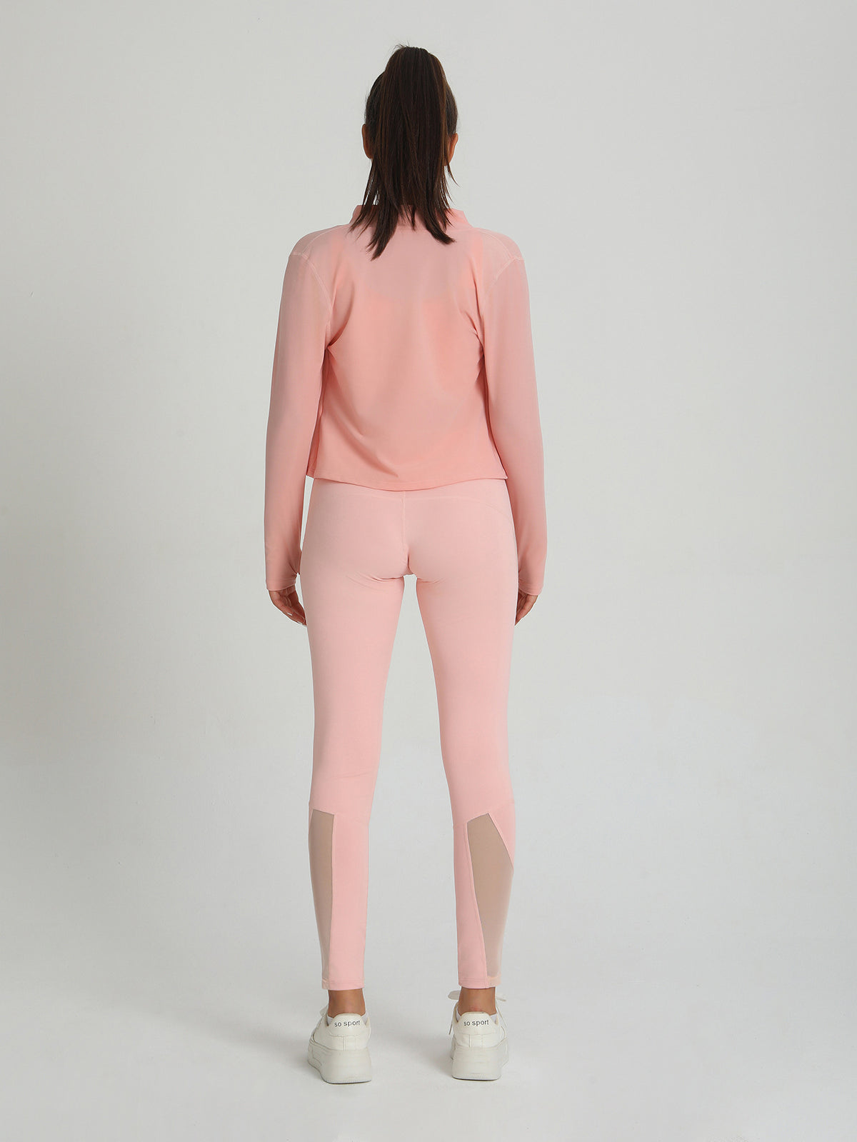 Peach-pink leggings and long-sleeve top with contrast mesh panels, back view