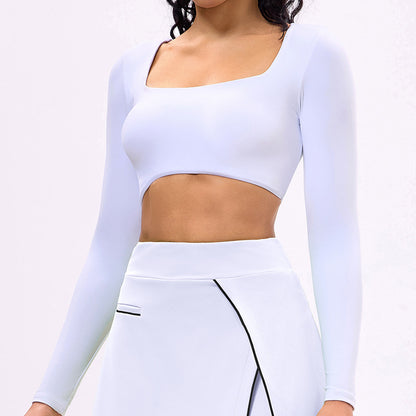 White long-sleeve sports crop top with square neckline and white tennis skirt with side slit