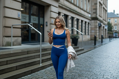 Woman wearing a blue tank top with white trim on a plain background