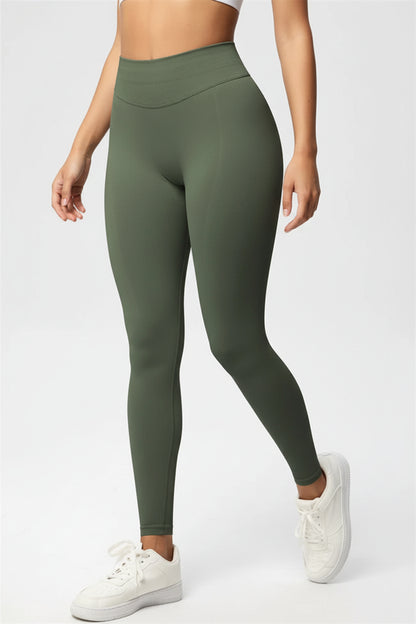 Person wearing green leggings and white sneakers on a light gray background