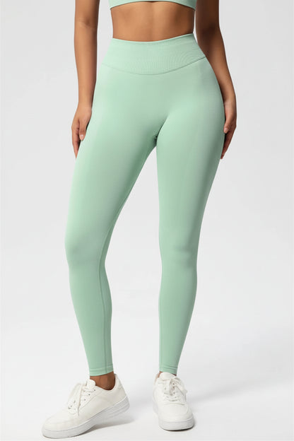 Person wearing light green leggings with a logo on a white background