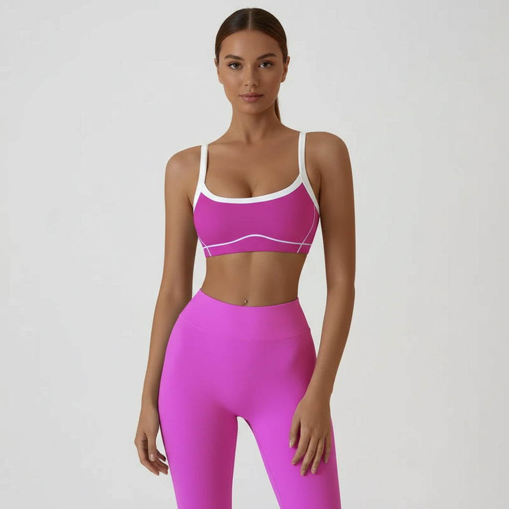 Woman wearing a pink sports bra and leggings set on a plain background