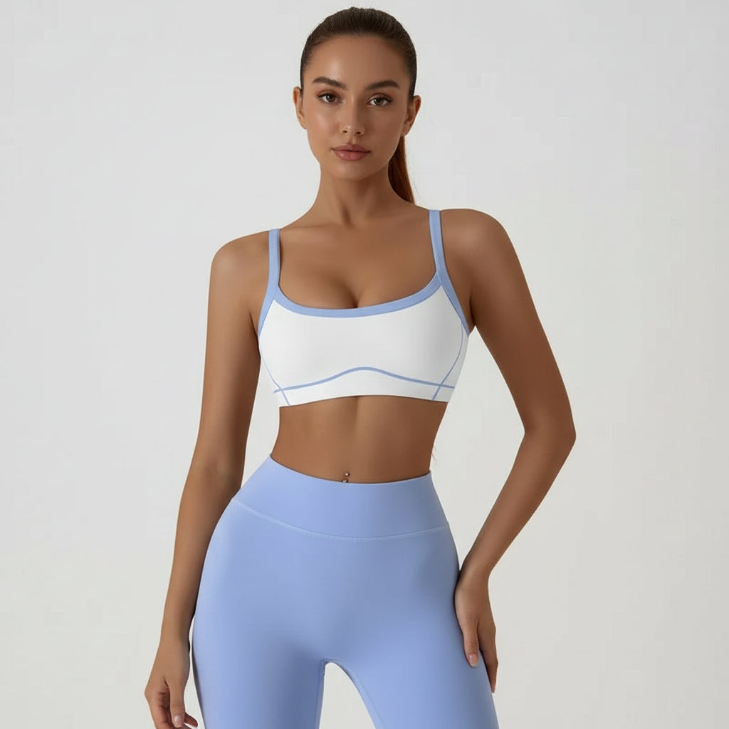 Person wearing a white sports bra with blue trim and matching leggings on a plain background