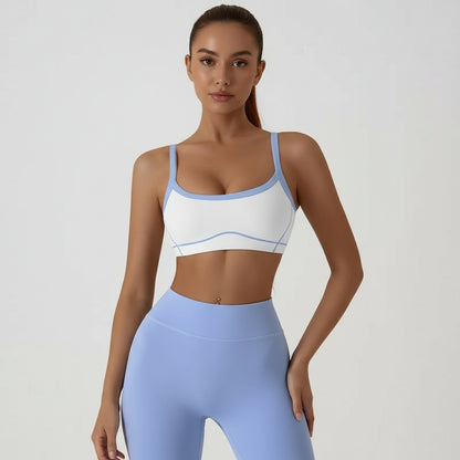 Person wearing a white sports bra with blue trim and matching leggings on a plain background