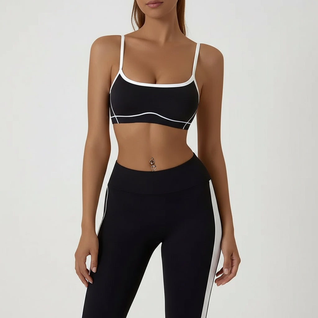 Black sports bra and leggings with white accents on a plain background