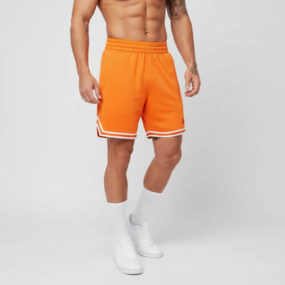 Person wearing bright orange shorts with white trim on a plain background