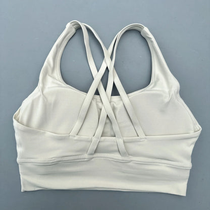 Women's cross-back padded sports bra in white with crisscross back straps and wide band.