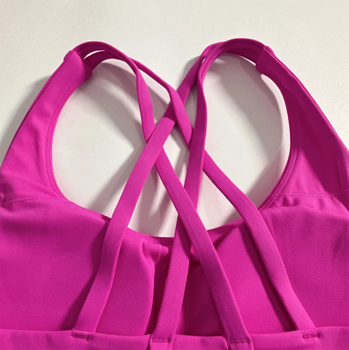 Magenta sports bra showing crisscross cross-back straps with padded scoop neckline.