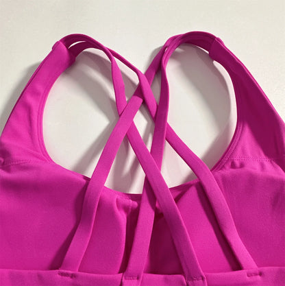Magenta sports bra showing crisscross cross-back straps with padded scoop neckline.