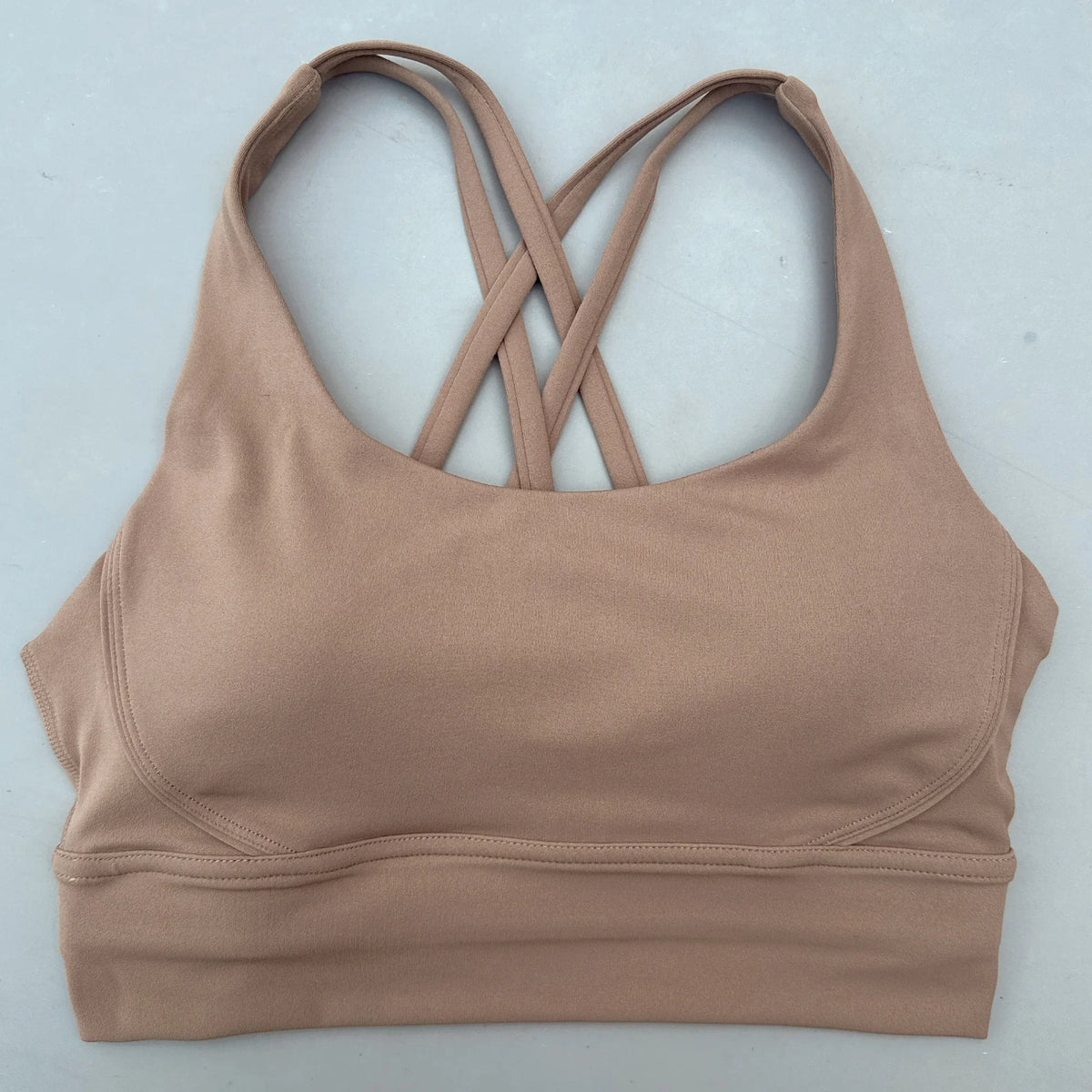Tan padded sports bra with crisscross cross-back straps and wide supportive hem.