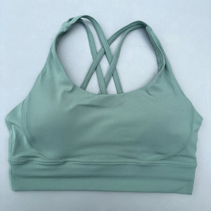 Sage green padded sports bra with crisscross cross-back straps and smooth elastic hem.