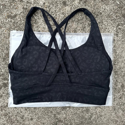 Women's padded cross-back sports bra in dark patterned fabric with crisscross back straps