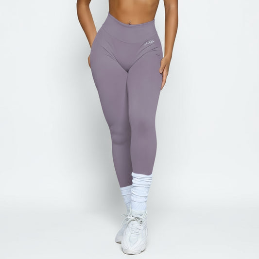 Person wearing purple leggings and white sneakers against a light gray background