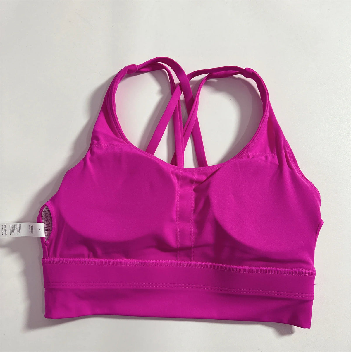 Women's cross-back padded sports bra in bright fuchsia pink with crisscross back straps.
