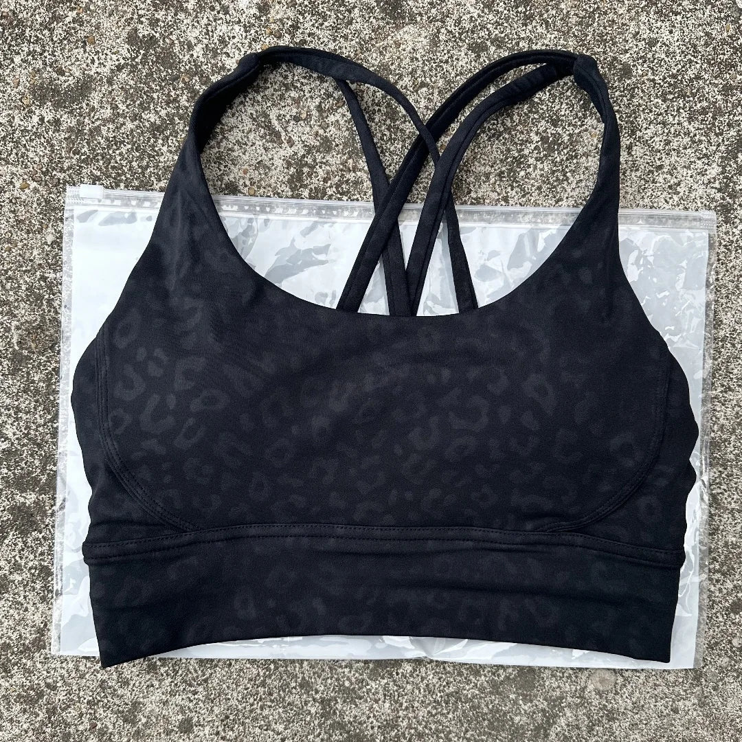 Navy padded sports bra with cross-back crisscross straps and allover spotted texture.